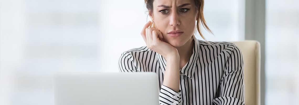 Confused businesswoman annoyed by online problem looking at laptop